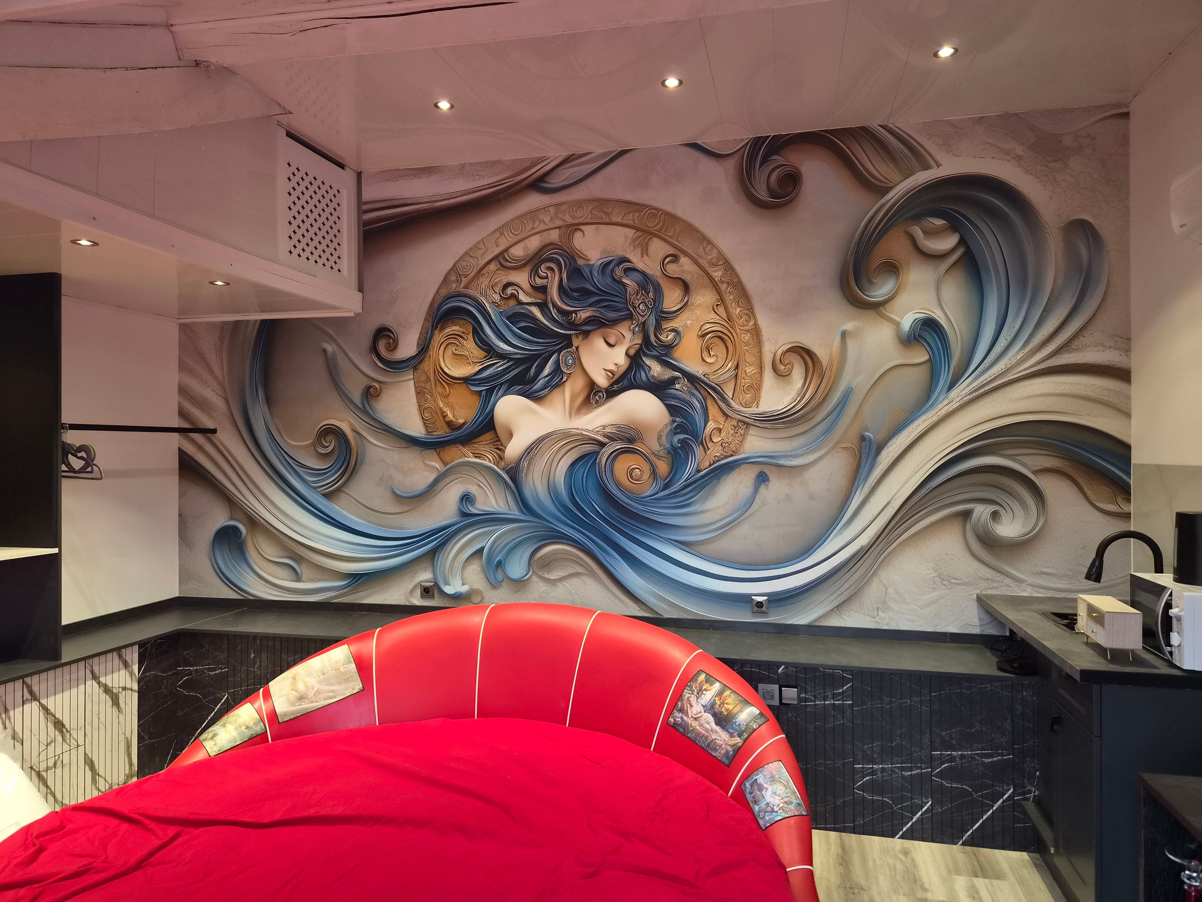 A room with a mural of a woman on the wall, a red upholstered chair, and a black marble countertop.