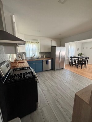 A modern kitchen with a gas stove, stainless steel appliances, and a dining area with a table and chairs.