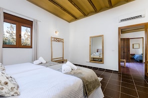 Een hotelkamer met een groot bed, een houten hoofdeinde, een spiegel en een raam met gordijnen.