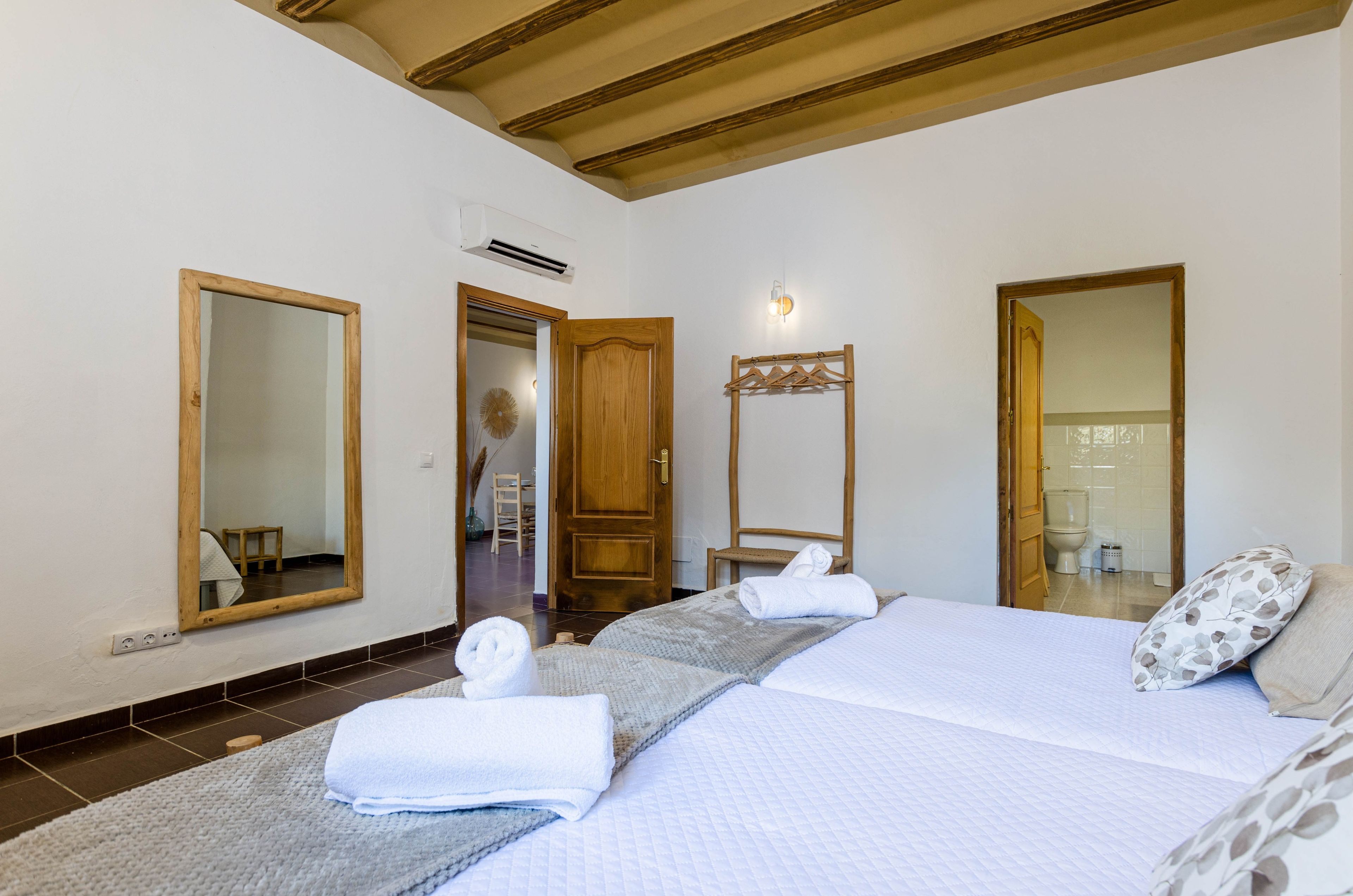 Habitación de hotel con cama, dos espejos, una puerta de madera y una toalla sobre la cama.