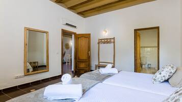 Habitación de hotel con cama, dos espejos, una puerta de madera y una toalla sobre la cama.