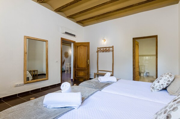 Une chambre d’hôtel avec un lit, deux miroirs, une porte en bois et une serviette sur le lit.