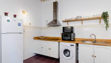Una cocina compacta con refrigerador, microondas, lavadora y pileta.