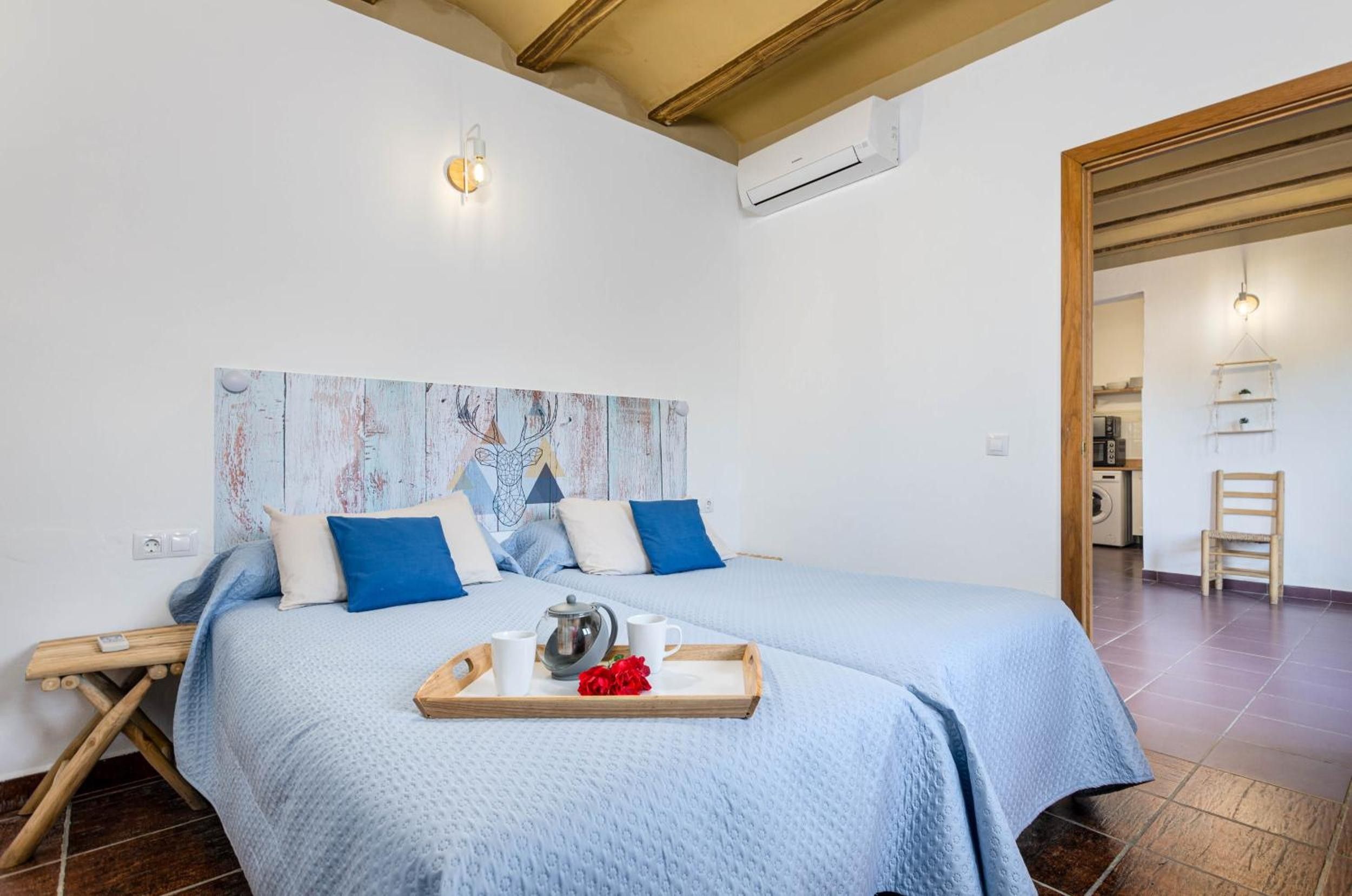 A bedroom with a bed, a tray with a teapot and cups, and a painting on the wall.