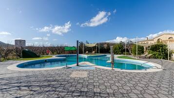 Una piscina con un diseño curvo único, rodeada por una zona pavimentada con suelo de baldosas estampadas.