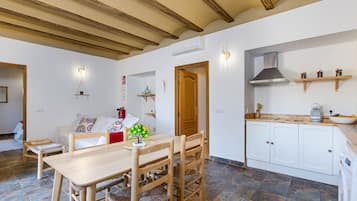 A modern kitchen with white cabinets, a wooden dining table, and a built-in stove.