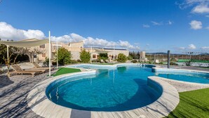 En swimmingpool med cirkulært design, omgivet af en patio med liggestole.
