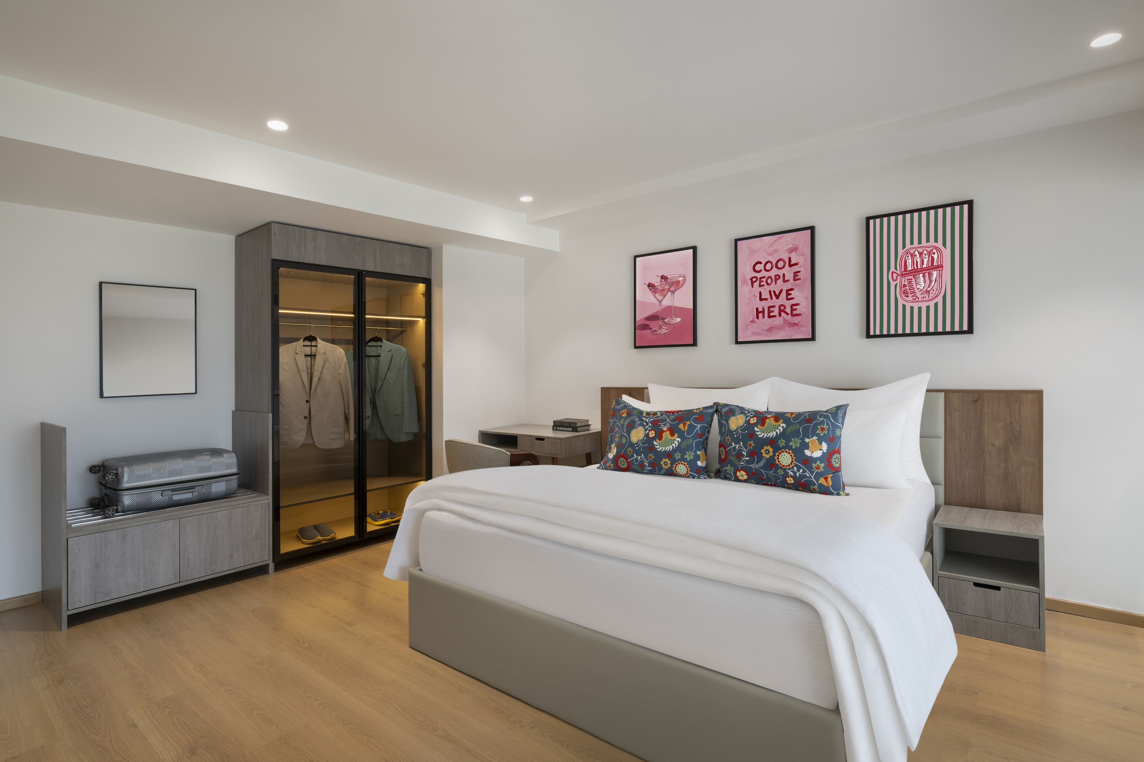A modern bedroom with a large bed, a walk-in closet, a desk, and artwork on the wall.