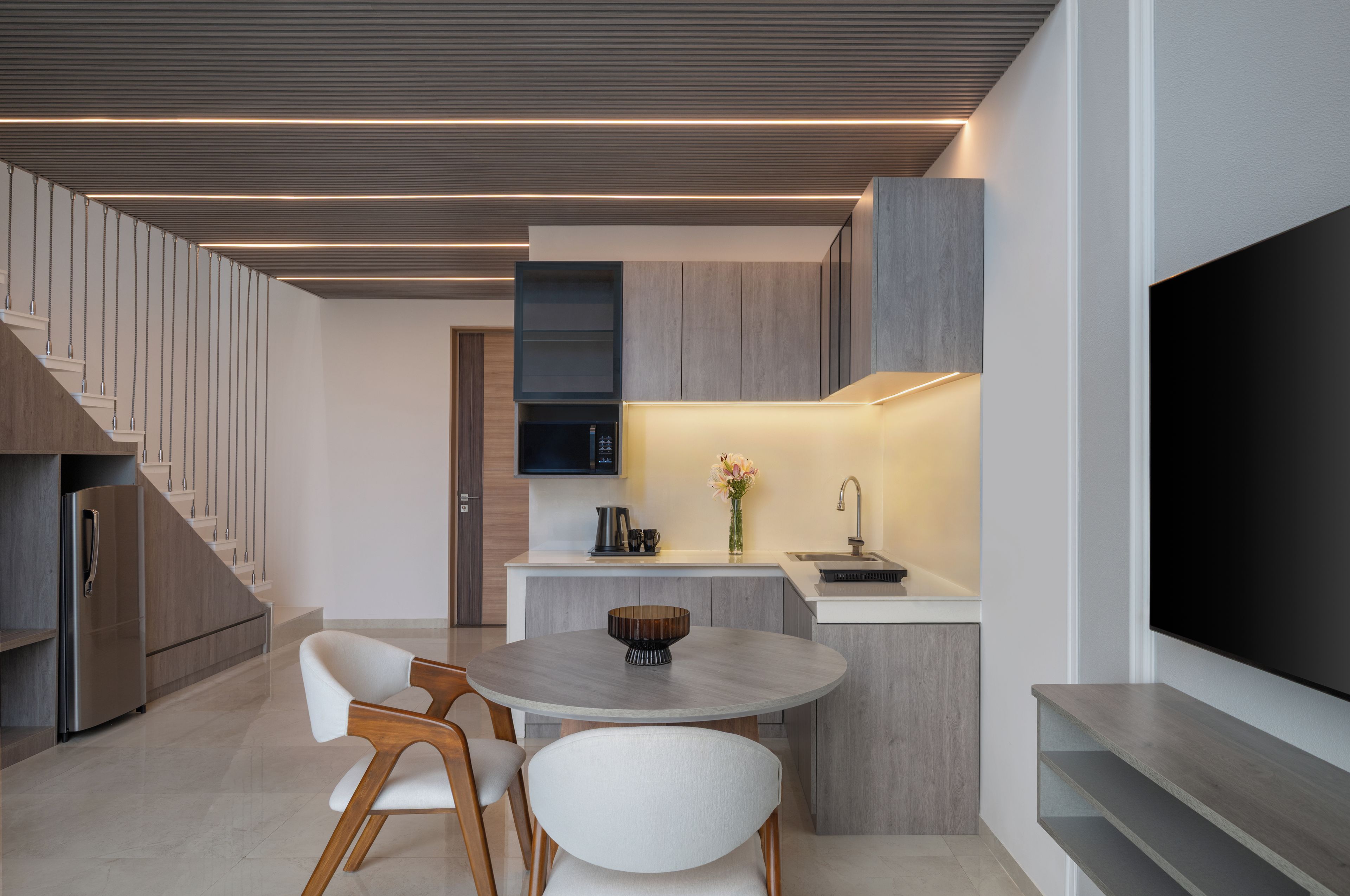 Una cocina moderna con comedor, televisor de pantalla plana y escalera.