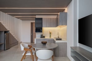 Una cocina moderna con comedor, televisor de pantalla plana y escalera.