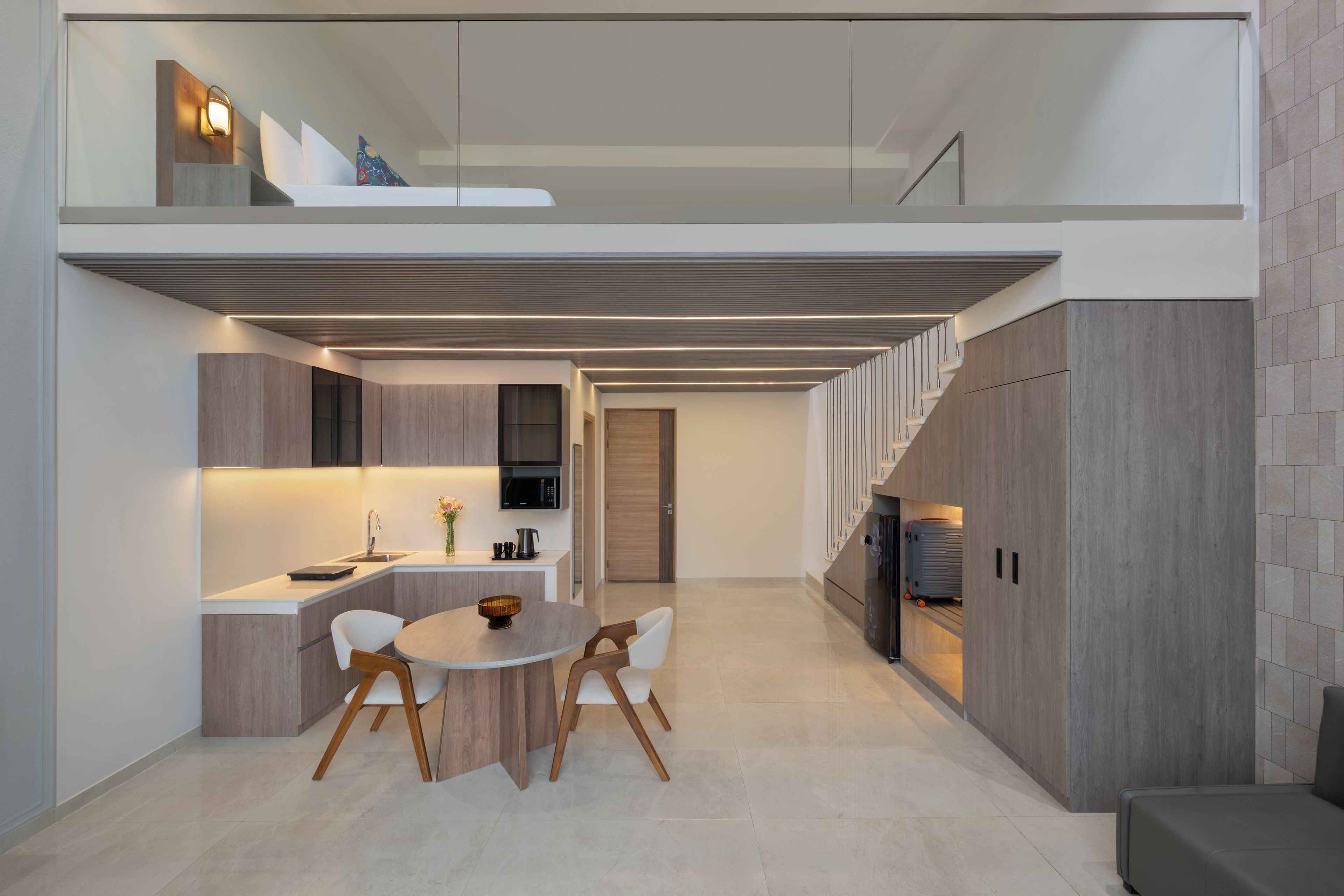 Una cocina moderna con una isla integrada, un comedor con mesa y sillas redondas, y una escalera que lleva a un nivel superior.