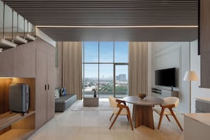 A modern living room with a large window, a dining area, and a TV.