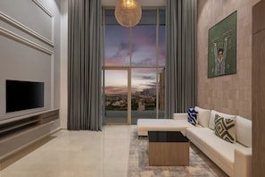 Una sala de estar moderna con un televisor de pantalla plana, un sofá, una mesa de centro y un ventanal con vistas a la ciudad.