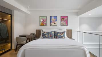 Una habitación de hotel moderna con una cama, un escritorio y una silla. Hay tres obras de arte enmarcadas en la pared.