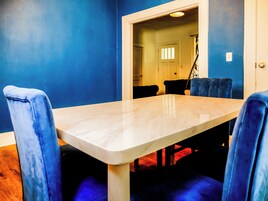 Un área de comedor con una mesa de mármol y sillas tapizadas en azul.