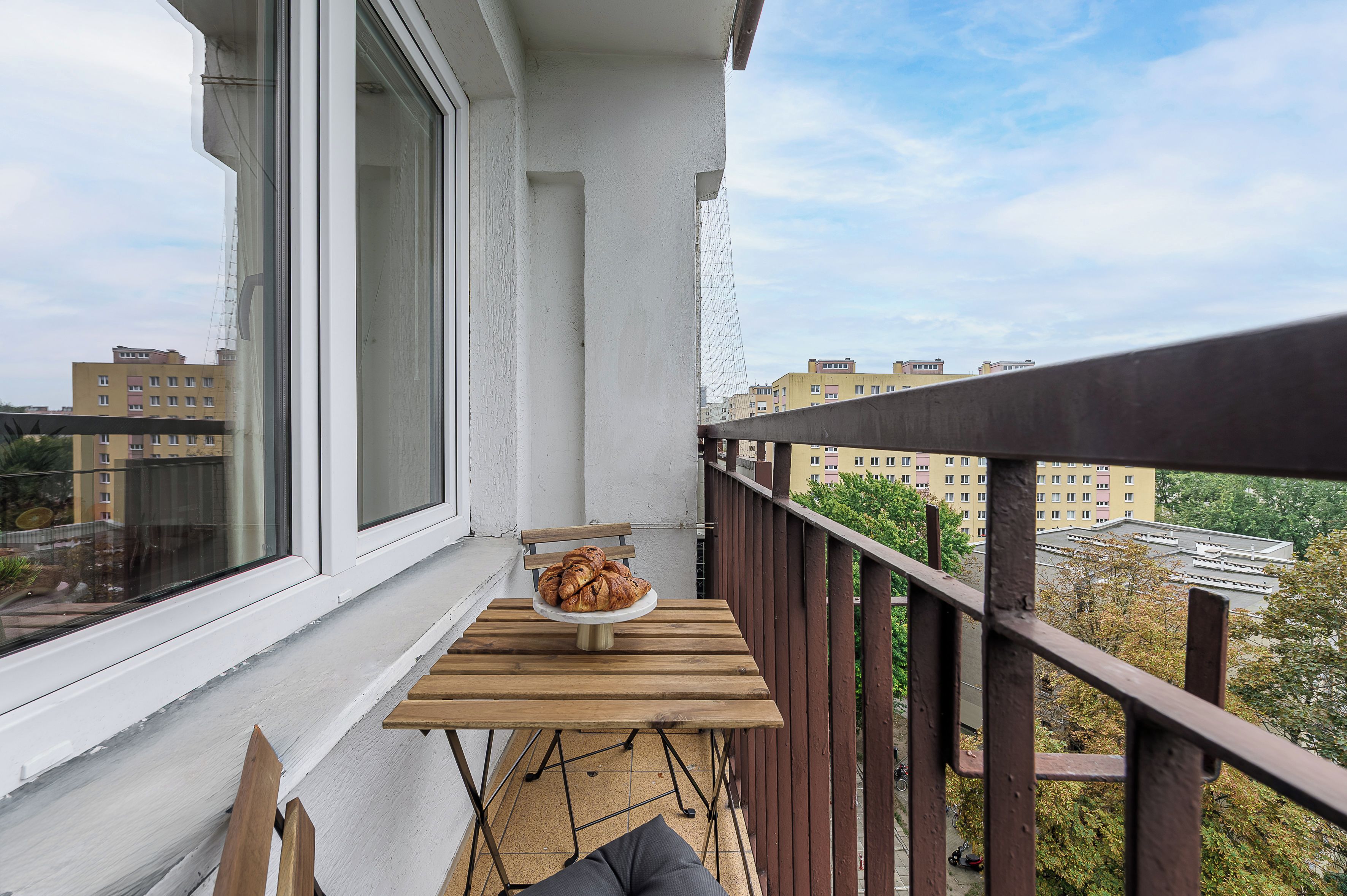 Varanda com mesa e cadeira, vista para a cidade.