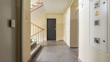 A hallway with a staircase, a door, and a utility panel.