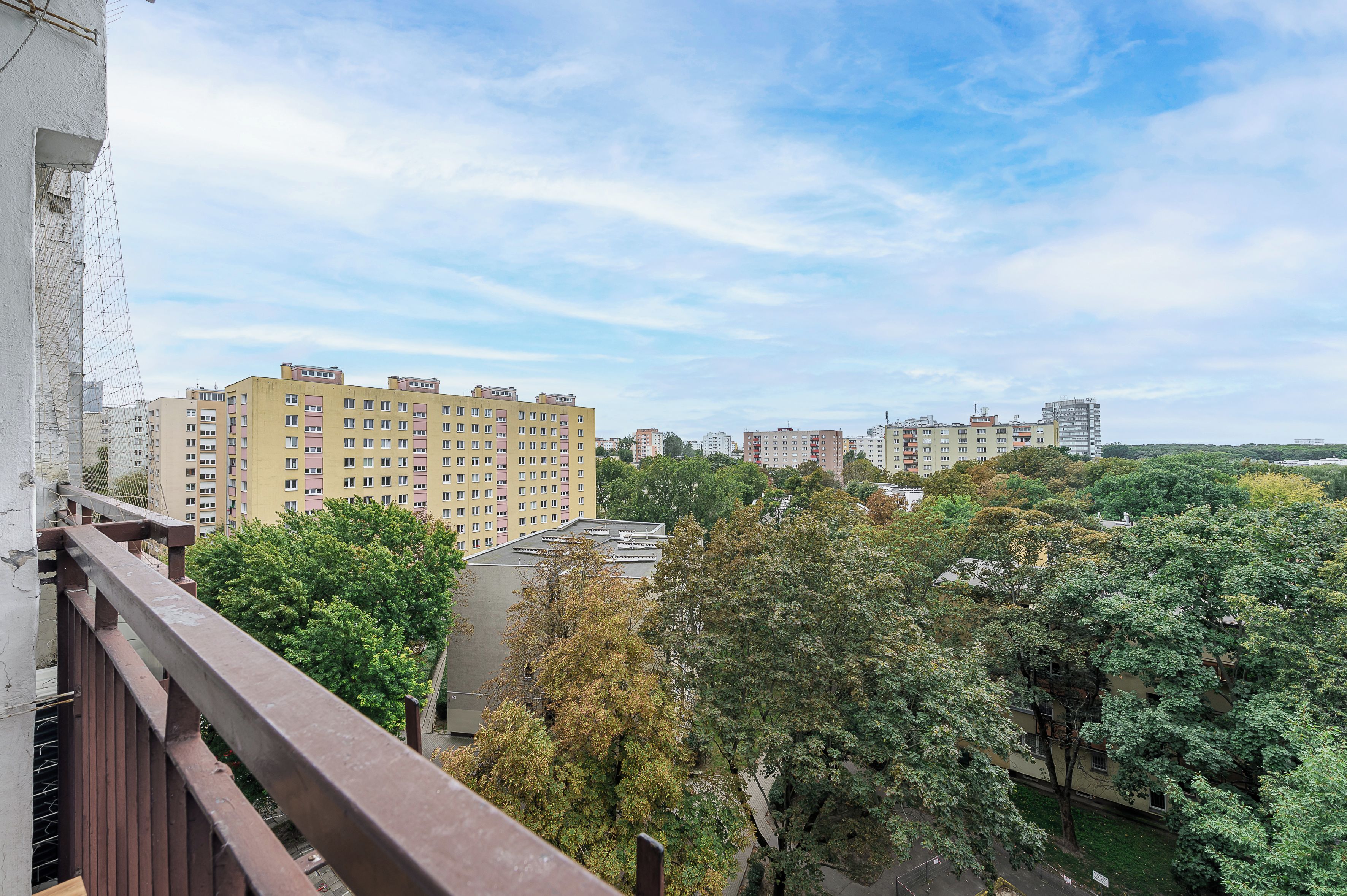 A residential area with multiple apartment buildings, trees, and a clear sky.