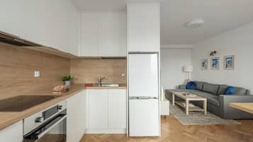 Cozinha moderna com armários brancos, forno embutido e geladeira.