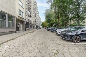 Rua residencial com carros estacionados e edifícios altos.
