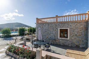 Un bâtiment en pierre doté d’un balcon, d’un espace extérieur aménagé pour s’asseoir et offrant une vue sur une colline.