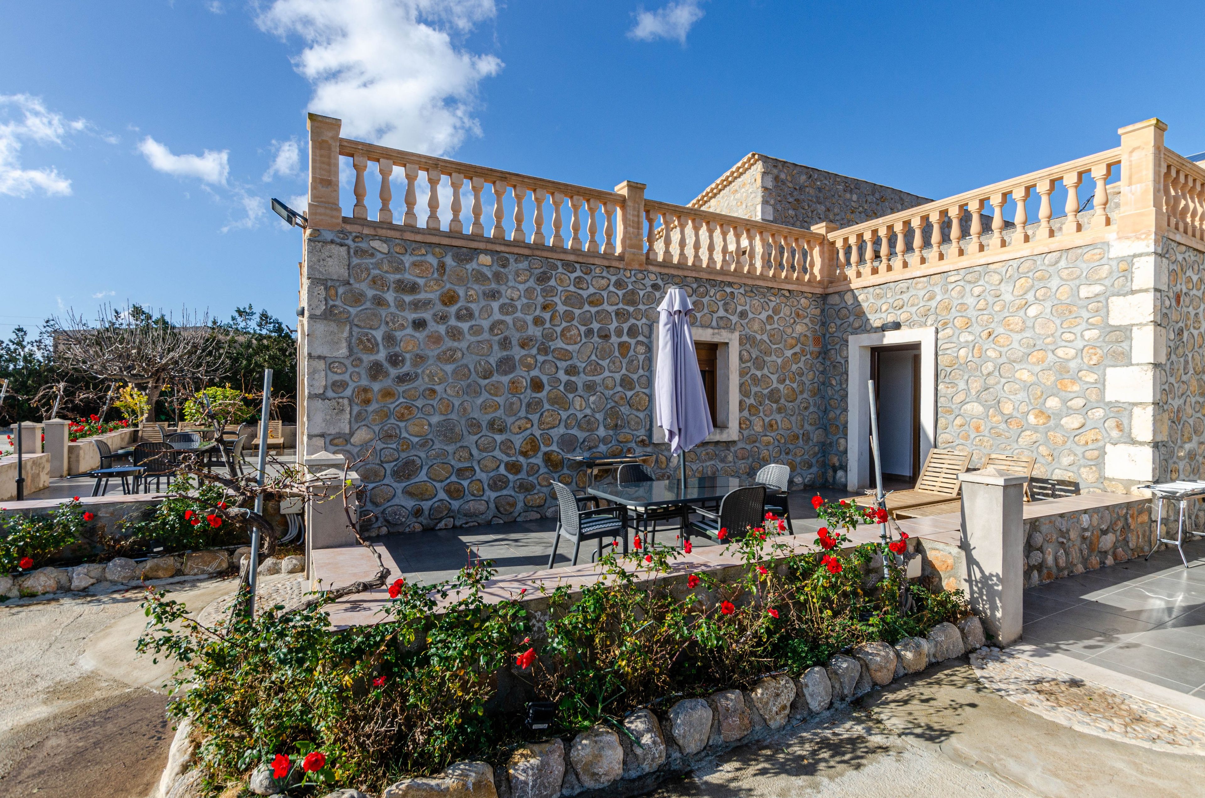 A stone building with outdoor seating and a balcony.
