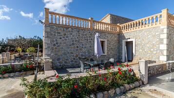 A stone building with outdoor seating and a balcony.
