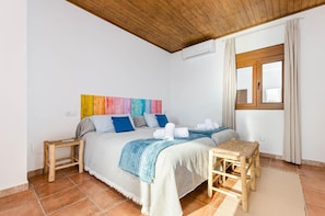 Une chambre à coucher avec un lit, deux tables de chevet, une fenêtre avec des rideaux et une décoration murale colorée.
