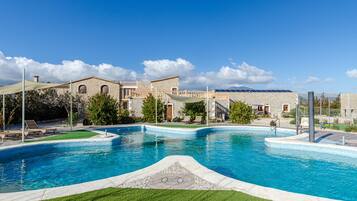 Une piscine avec, en arrière-plan, un bâtiment à la façade en pierre.