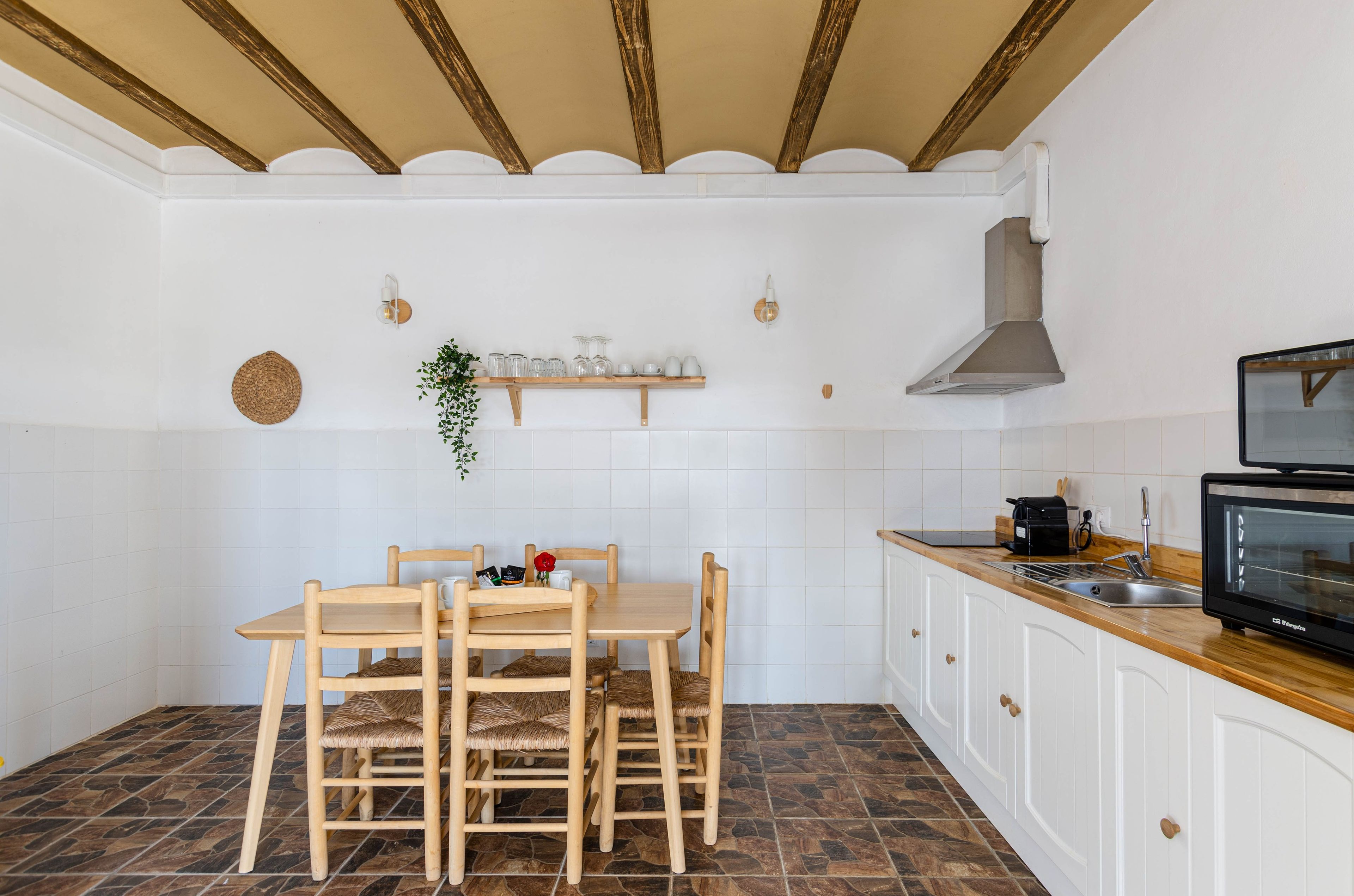 Una cocina con una mesa de comedor, sillas, un microondas y un fregadero.