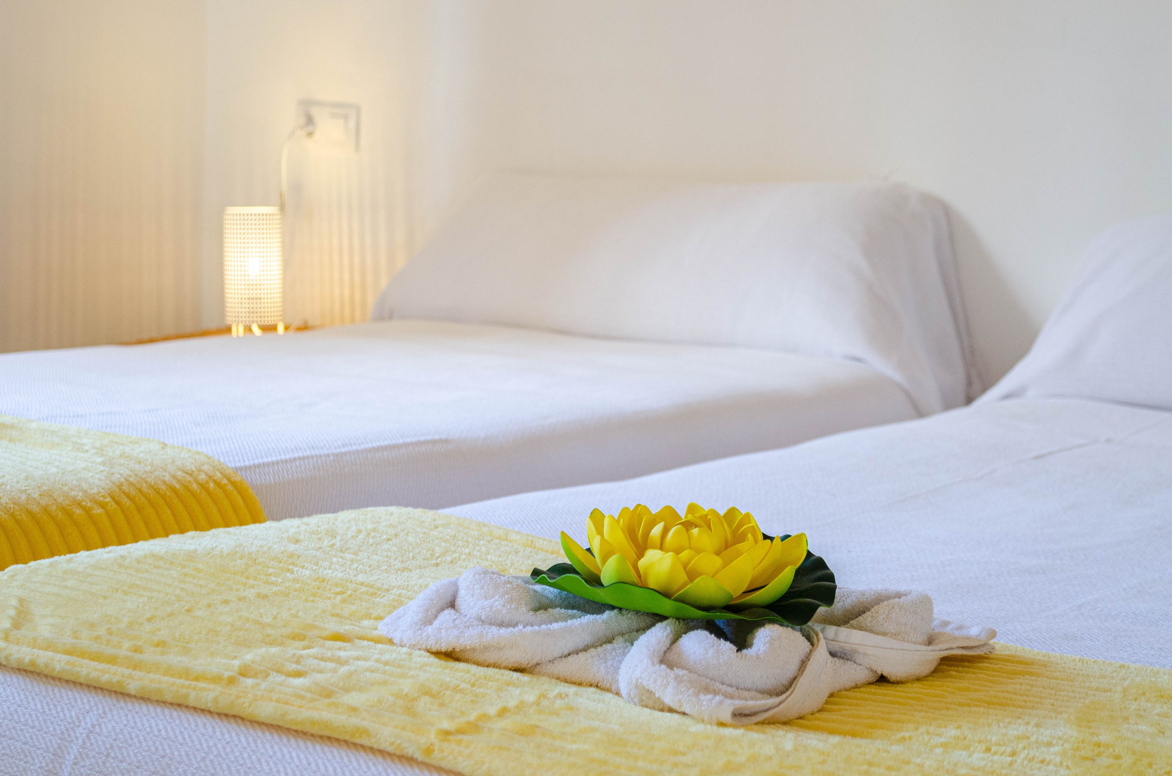 Habitación de hotel con dos camas, una mesita de noche y una lámpara de pared.