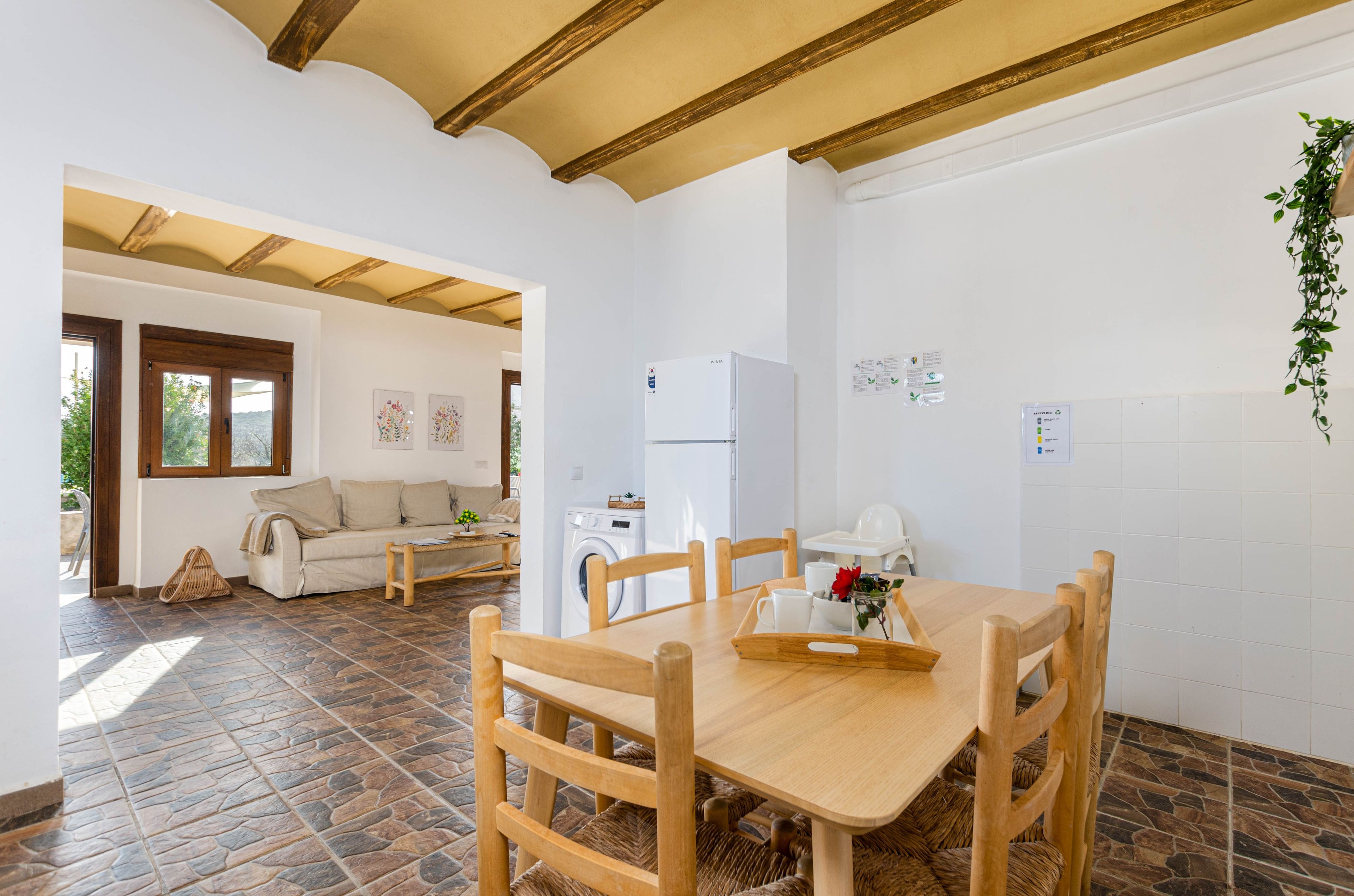 A spacious living area with a dining table, chairs, a sofa, and a washing machine.