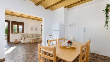 A spacious living area with a dining table, chairs, a sofa, and a washing machine.