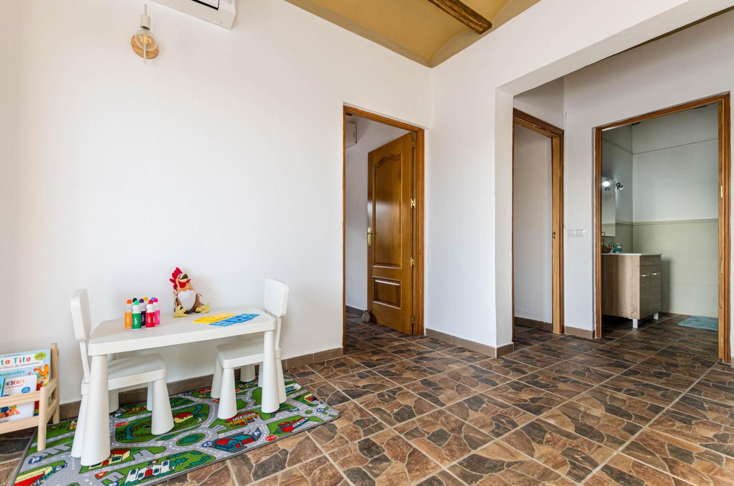 A room with a white table, chairs, and children's toys. There are two doors leading to other rooms.