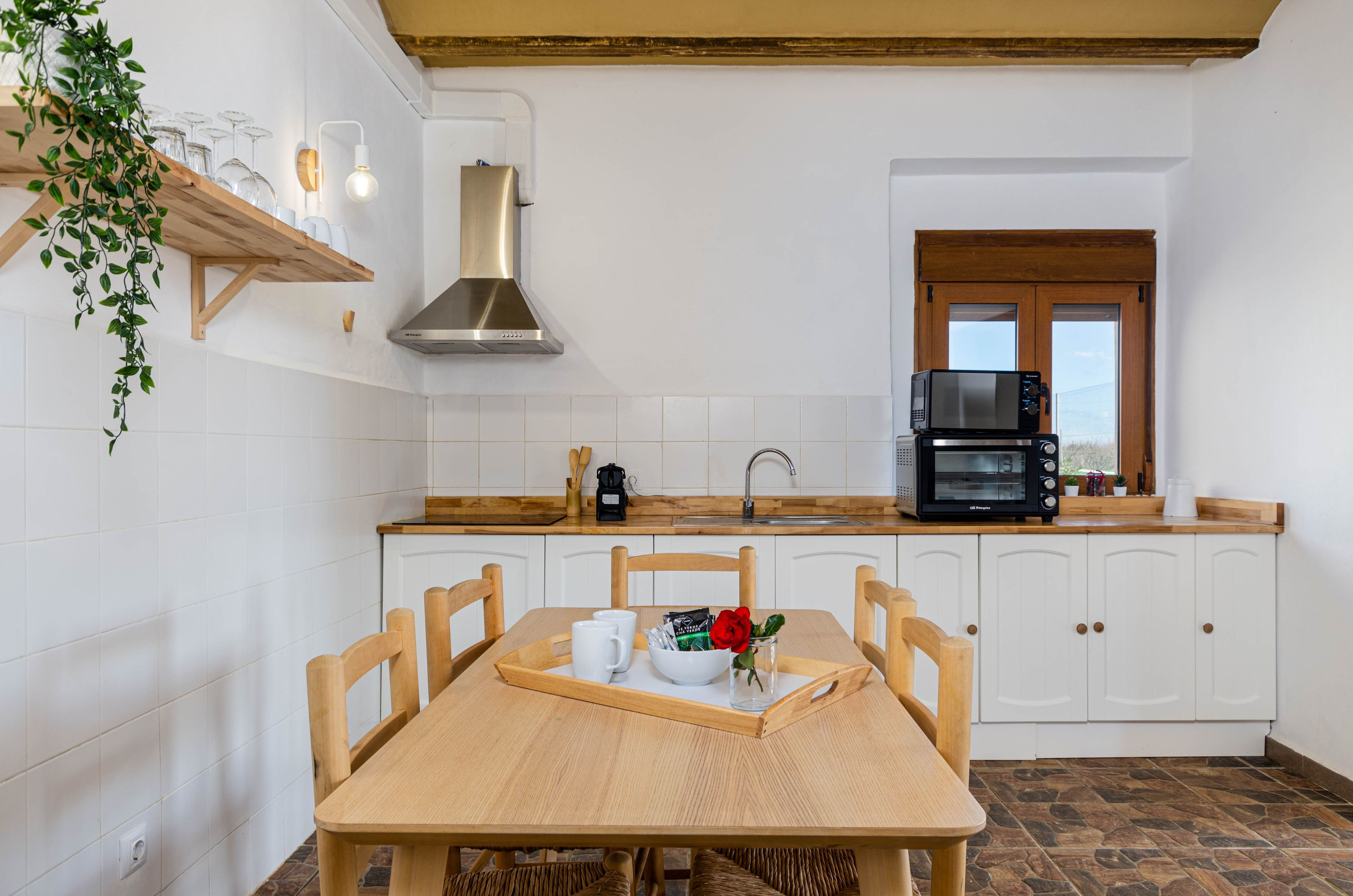 Eine Küche mit weißen Schränken, einem Holztisch und einem schwarzen Backofen.