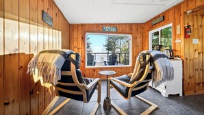 Een houten blokhut van binnen met twee schommelstoelen, een kleine tafel en uitzicht op het meer.