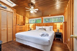 A wooden-paneled bedroom with a bed, two bedside lamps, a ceiling fan, and a window with blinds. - Waterfront 3-bedroom cottage with hot tub and AC (Gravenhurst)