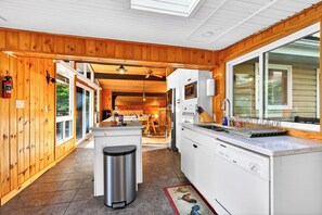 A modern kitchen with wooden paneling, a central island, and a large window. - Waterfront 3-bedroom cottage with hot tub and AC (Gravenhurst)