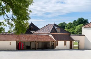 A building with a tiled roof, a covered area with a red structure, and a clear sky. - Holiday Home 'La Bourgogne - Grange Arthuis' with Shared Garden, Wi-Fi and Air Conditioning (Lavau)