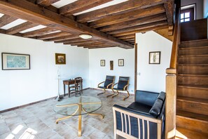 A room with a wooden ceiling, a glass table, two chairs, a sofa, and a staircase. - Holiday Home 'La Bourgogne - Grange Arthuis' with Shared Garden, Wi-Fi and Air Conditioning (Lavau)