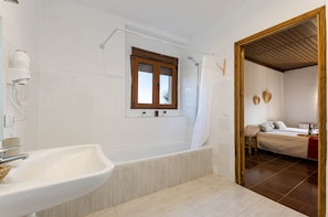 Een badkamer met een bad, een wastafel, een douche en een raam.