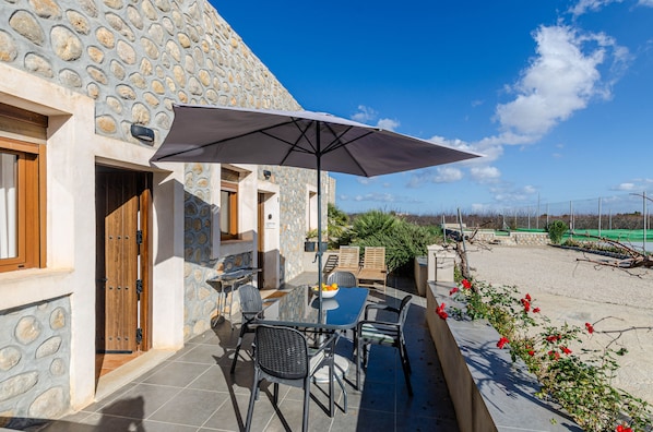 Een terras met een tafel, stoelen, een parasol en een stenen muur.