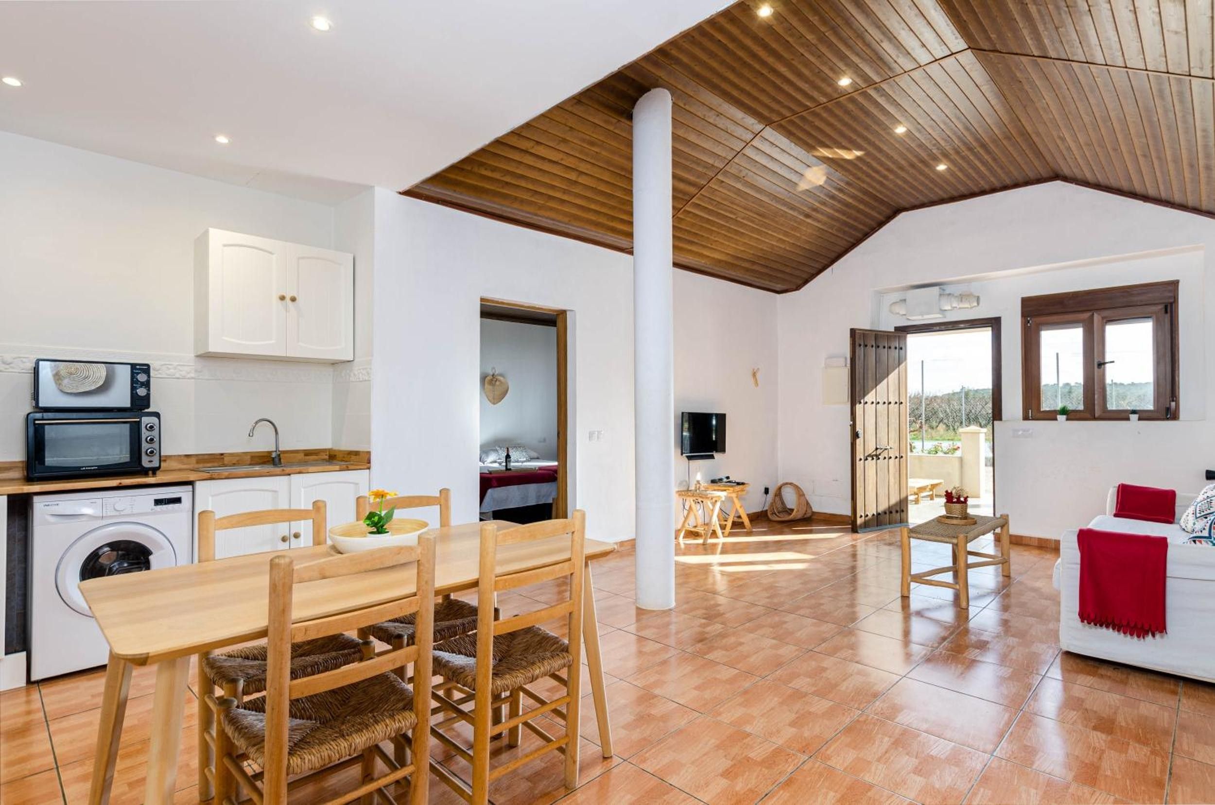 Un amplio salón con techo alto, una cocina con electrodomésticos modernos y un comedor con muebles de madera.