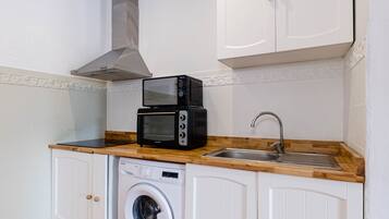 Una cocina compacta con microondas, tostadora, lavabo y lavadora.
