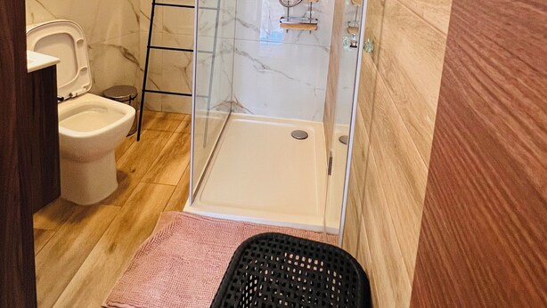 A bathroom with a glass-enclosed shower, a toilet, and a wooden floor. - St. Julian's Central Apartment 5 (St. Julian's)
