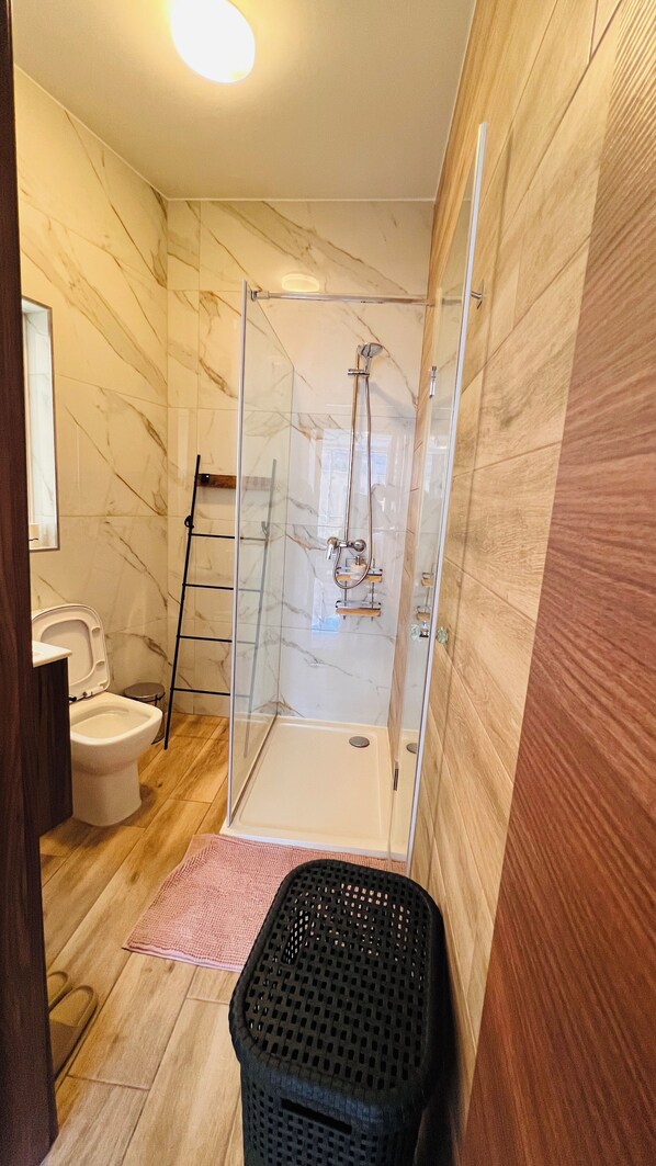 Ein Badezimmer mit einer Duschkabine, einer Toilette und einem Holzboden.