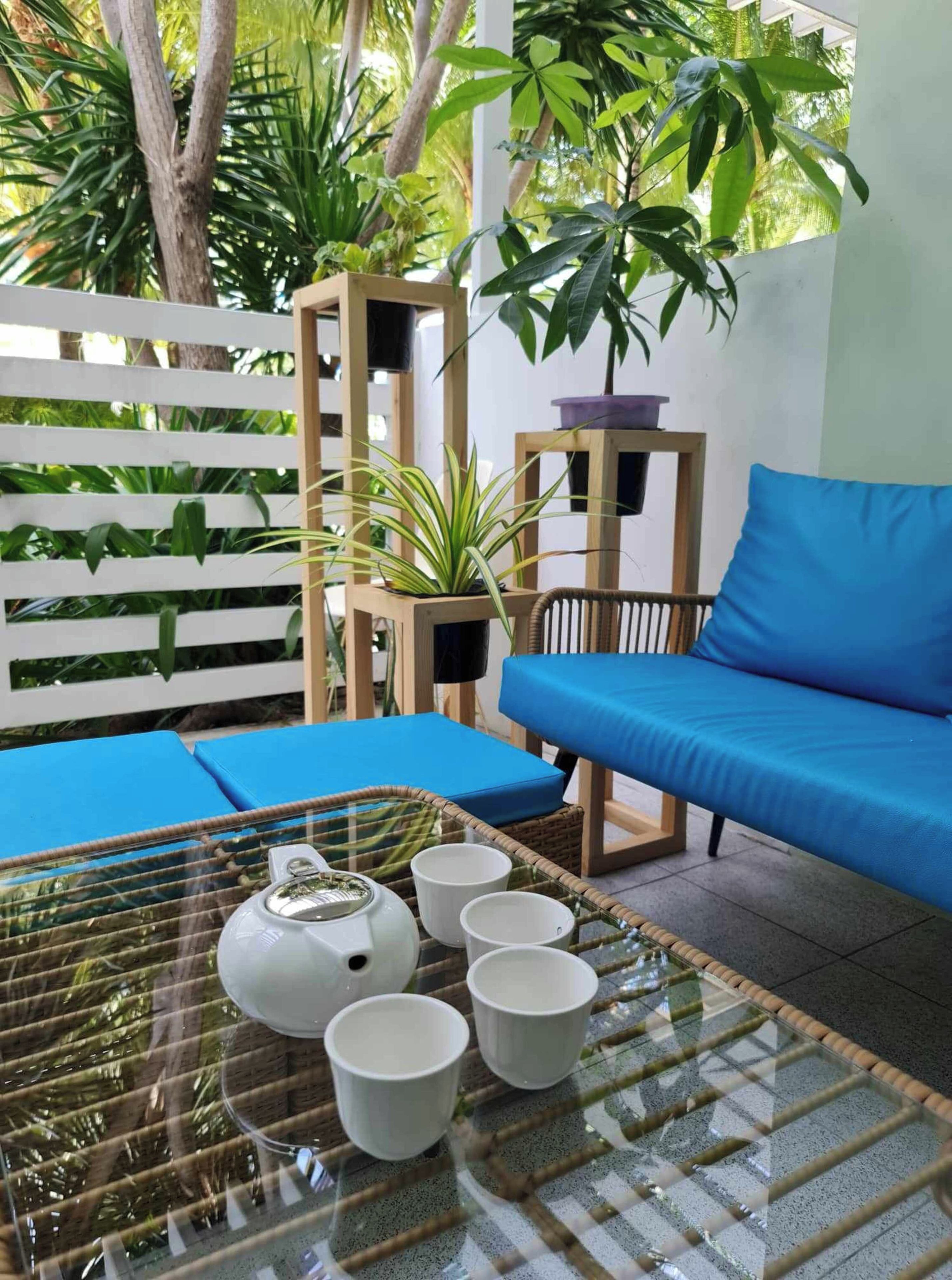 A room with a glass-top table, a blue sofa, and a white chair.