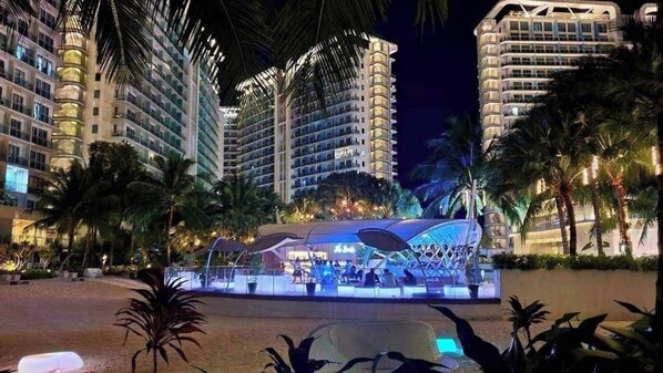 Un hotel con varios edificios altos, una piscina y palmeras.