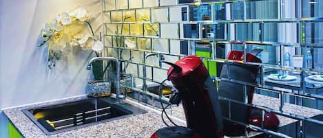 Una cocina moderna con encimera de granito, una cafetera roja y una campana extractora de acero inoxidable.