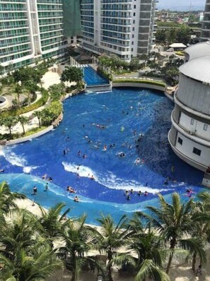 A large indoor swimming pool with multiple lanes, surrounded by palm trees and modern buildings. - 1BR Premium Suite (Parañaque)